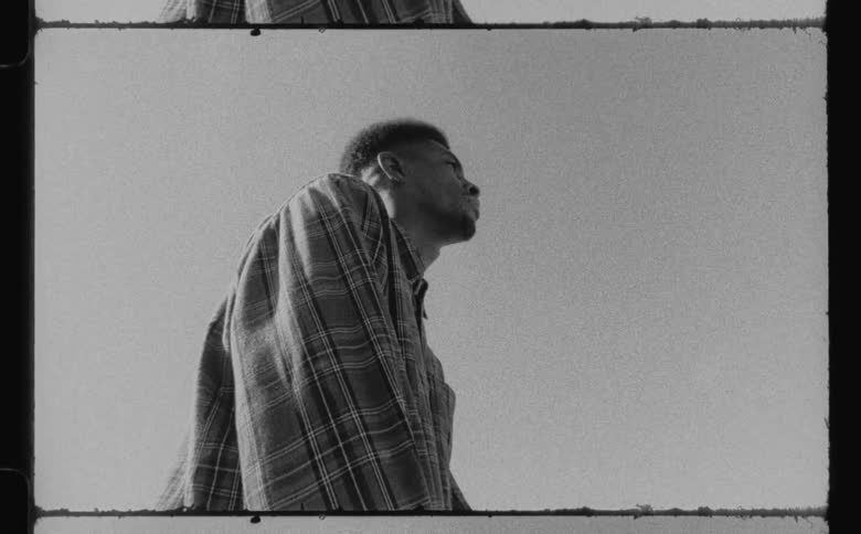A ground up view of a man standing in a striped shirt looking off into the distance