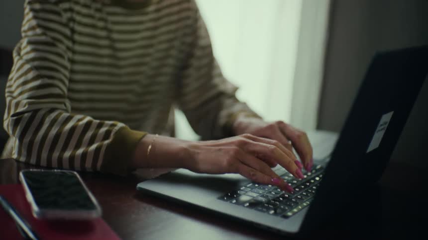 A woman sitting at her desk typing on her laptop