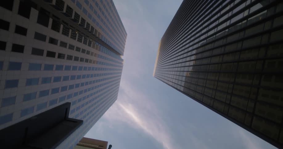Looking up at two tall buildings against a clear sky