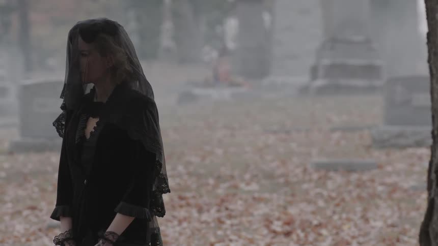 A veiled woman walks in a cemetery