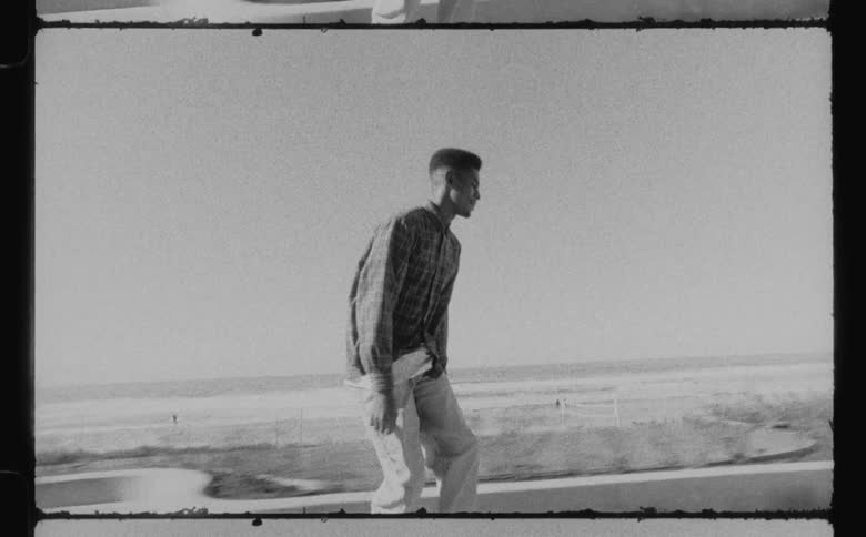 A man skateboarding along a walkway with the beach in the background