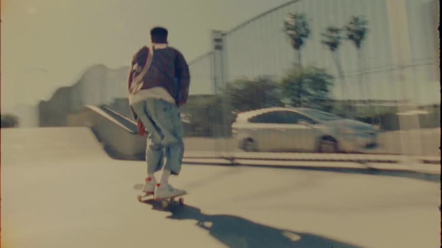 A man skateboarding in a park down a ramp and on a rail