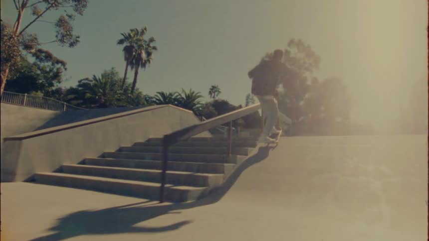 A skateboarder jumps onto a handrail in a skate park