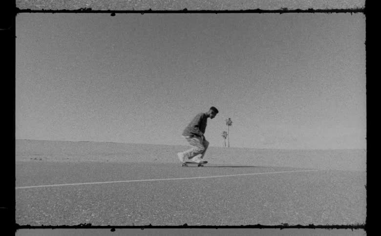 A male is skateboarding on tarmac outdoors