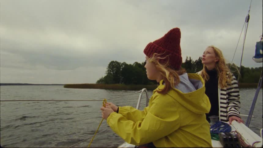 Mother and daughter travel on lake by boat on a cloudy day