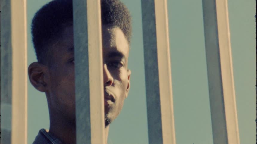 A man is standing outdoors near a fence