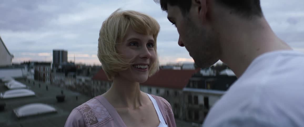 Young couple in love touch foreheads while standing atop a building in the morning