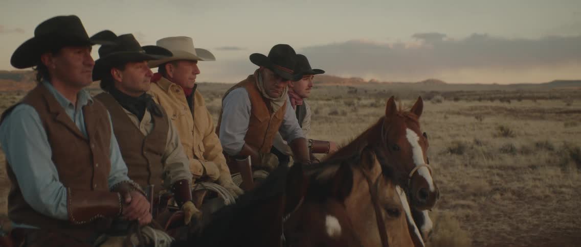 A group of men with their horses are outdoors on a field