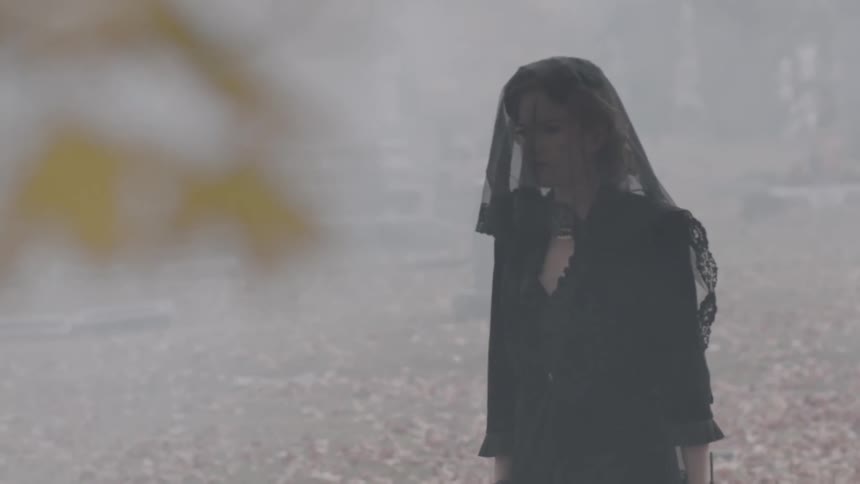 Woman dressed in black walking through a cemetery