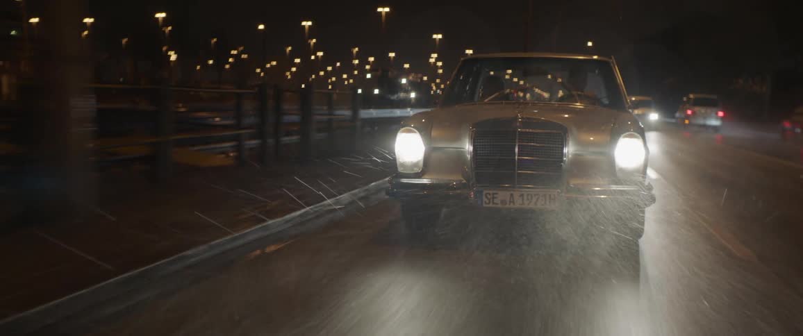 Young couple driving a vintage car on the rain in the highway at night