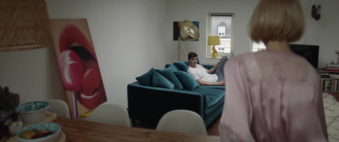 Man sitting on couch asks woman in pink robe to come in the living room