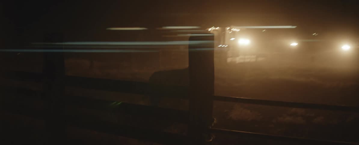 Silhouette of a bull running inside a corral against bright lights on a ranch at night