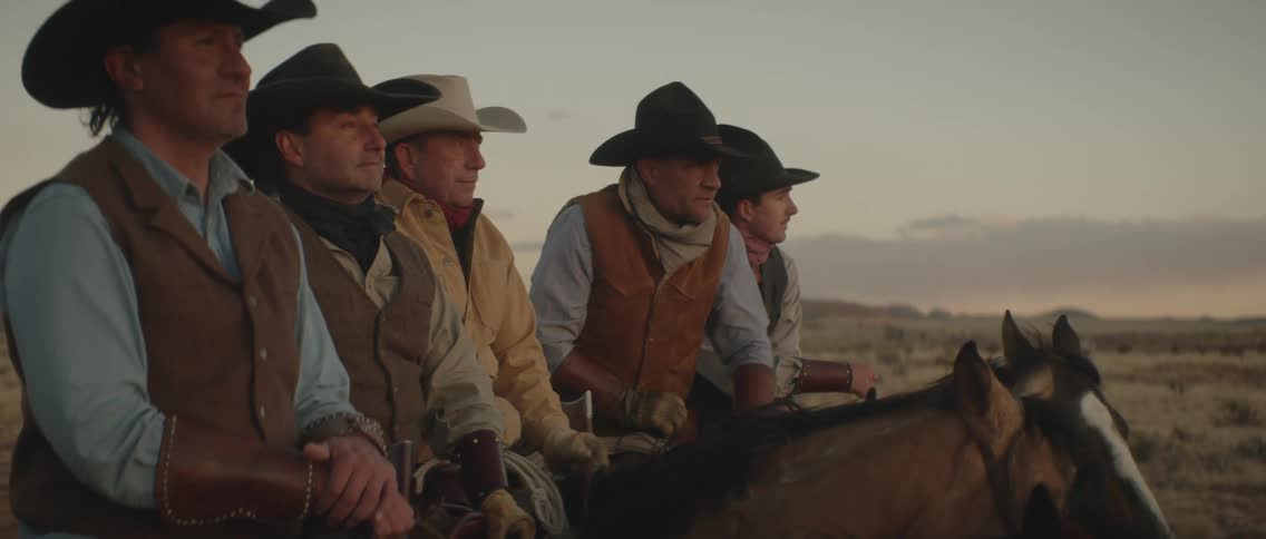 Five cowboys are outdoors with their horses