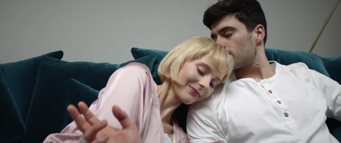Man and woman are cuddling on the couch together