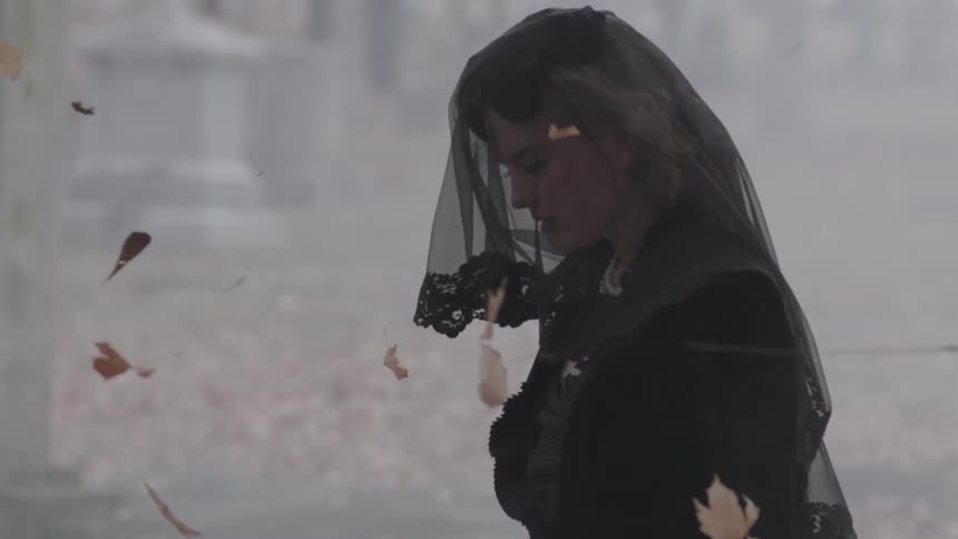 Woman dressed in black walking through a cemetery