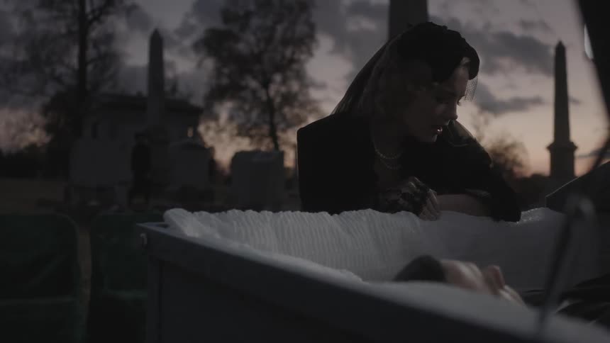 A woman cries into a coffin with a man in it