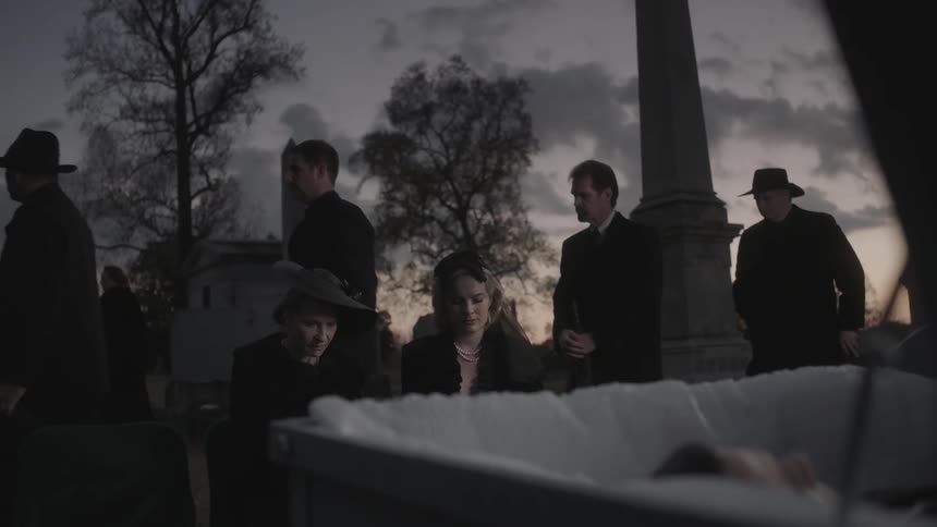 Mourners at a funeral file away from the burial site