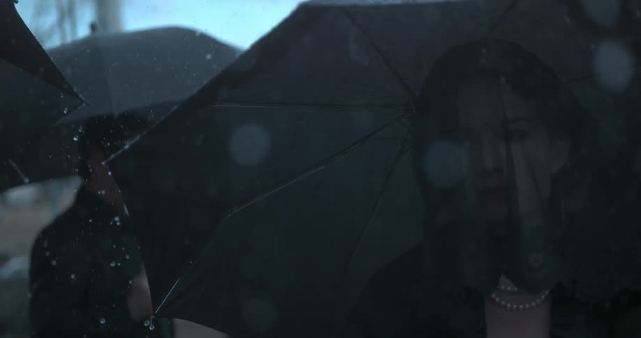 Rain falls on a group of people in black