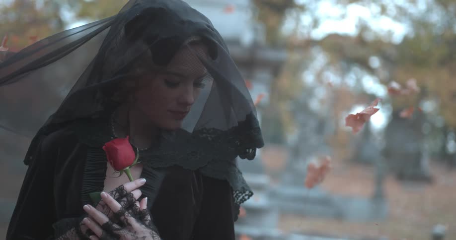 A woman stands outside holding a rose