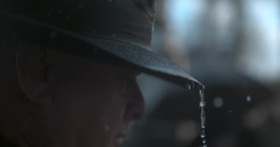 Rains falls down and drips off a man who's wearing a black hat