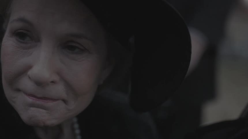 An older woman closes her eyes and purses her lips
