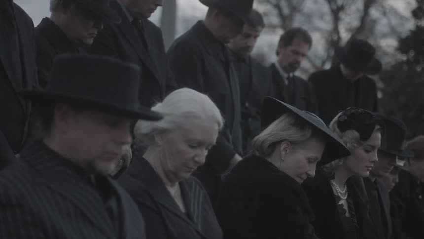 Men and women dressed in black bowing their heads