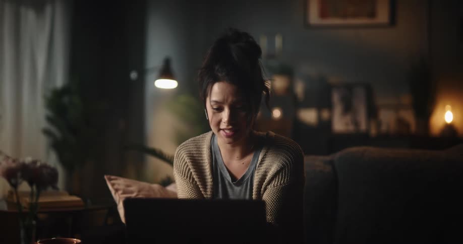 A woman talking on a laptop after looking at the camera