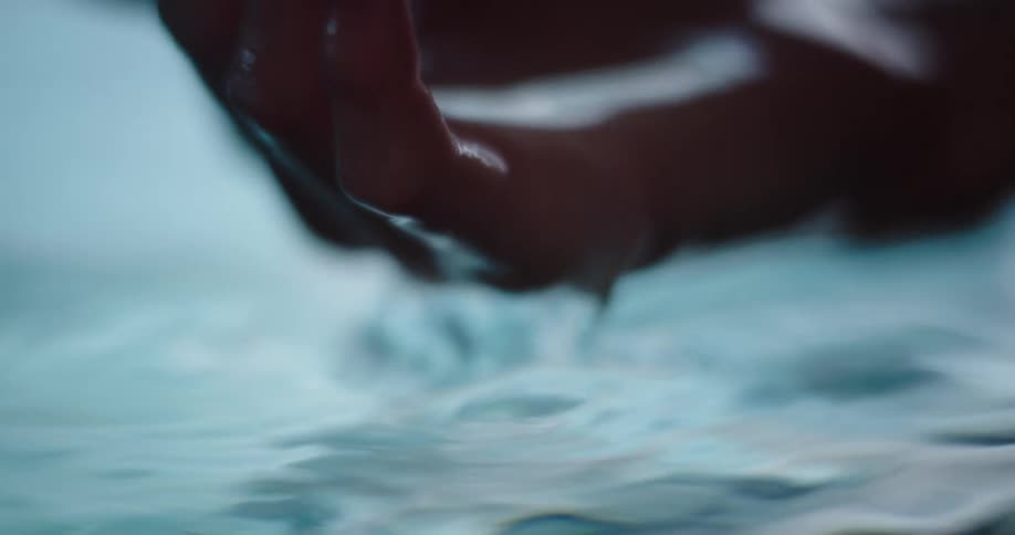 Hand dipping in and out of water cupping water and then releasing
