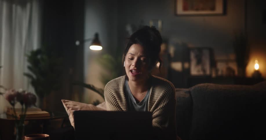 Woman sits on couch talking via laptop video conference
