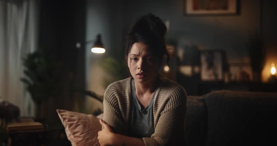 Sad woman sitting on couch makes video call and closes laptop in dark room