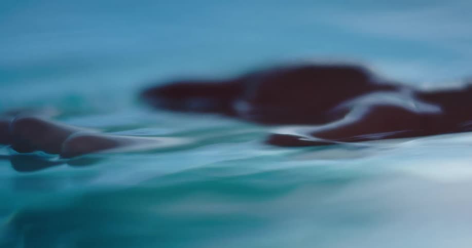 A person dipping their hand in rippling water