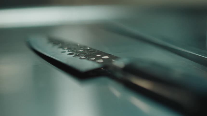 Zoom on a knife and a sharpener on a kitchen table