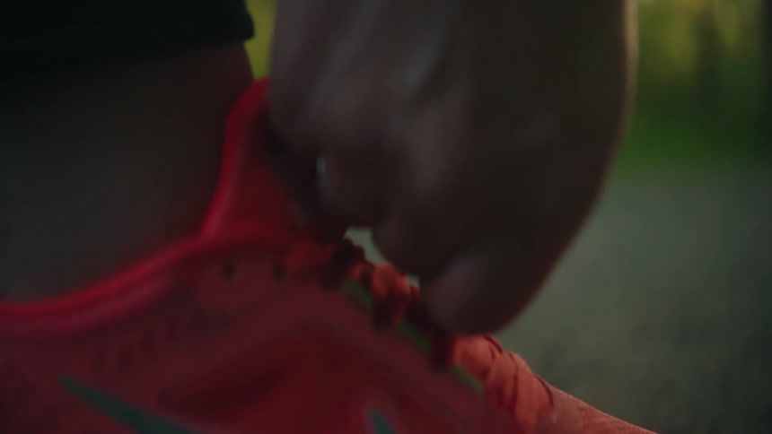 A woman holds the laces of her pink tennis shoes in her hands and ties them