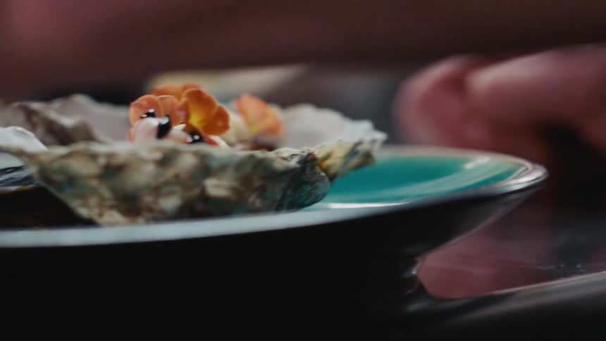 A man places flowers as decoration on top of oysters