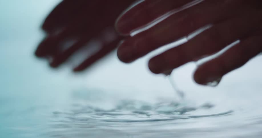 A woman cups water in her hands while in a pool