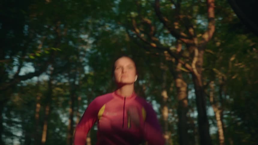 Woman jogs through woods under a blue sky