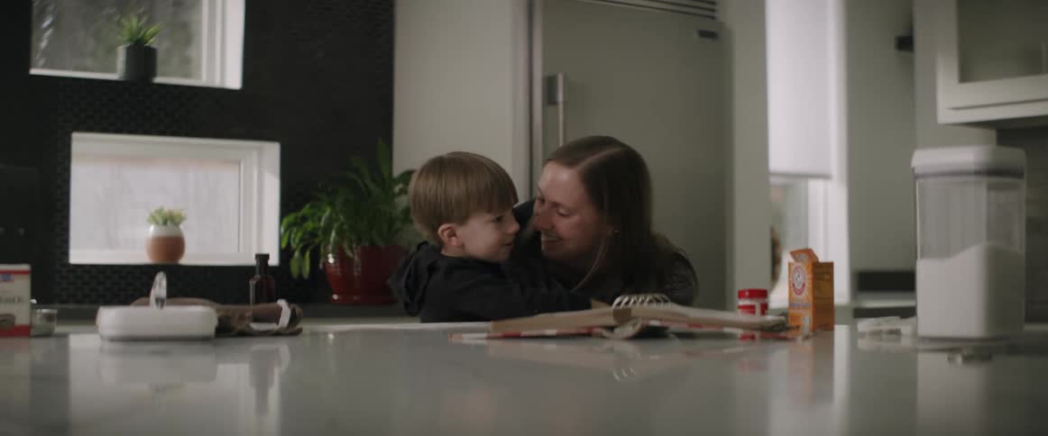 A woman kisses her son on the cheek while cooking in the kitchen