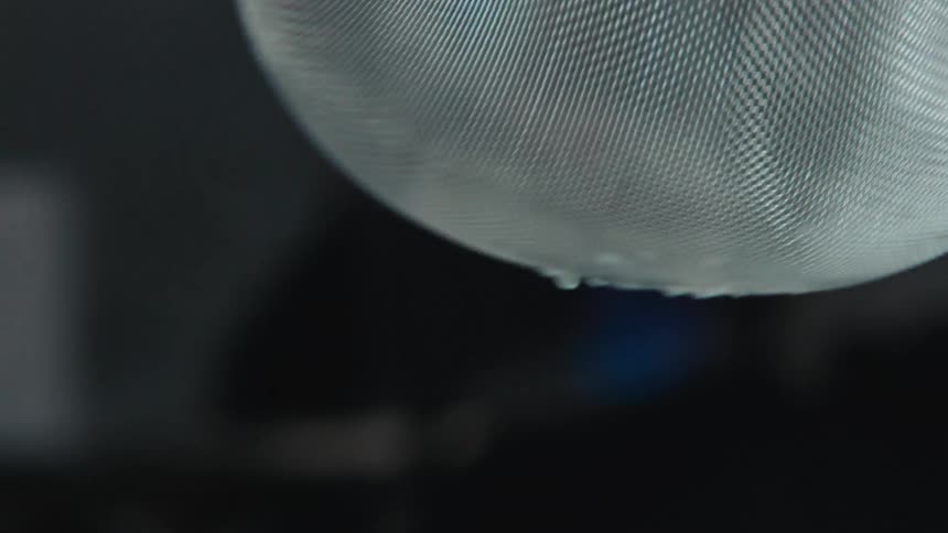 A person cutting a lemon in half and then squeezing the juice from it into a strainer