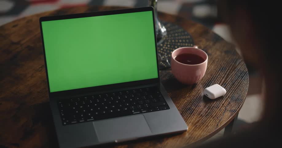 Woman puts in earbuds while she sits and watches laptop screen