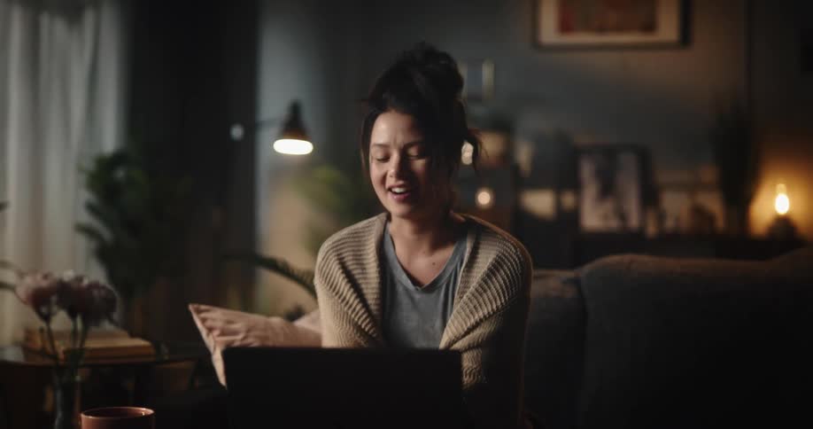 Happy woman emotionally talks on a video call through her laptop in the living room at home