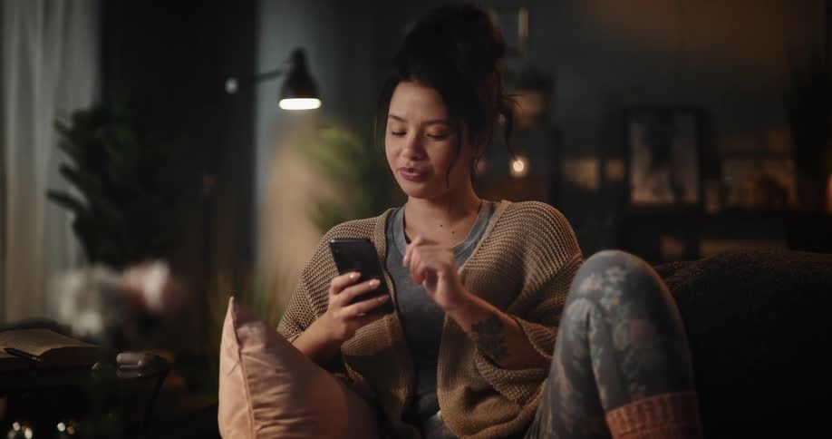 Woman sitting on couch uses smartphone in the living room