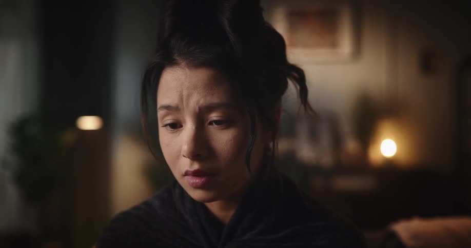 A young woman looks very sad as she holds her cell phone