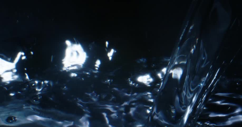 Pouring water sparkles as it splashes and droplets fly into the air as they reflect the light