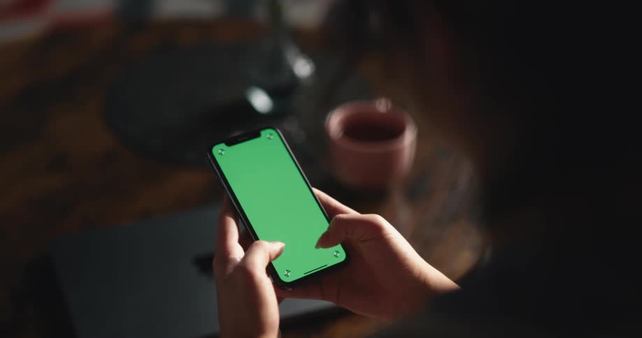Woman with dark hair sitting on couch uses smartphone