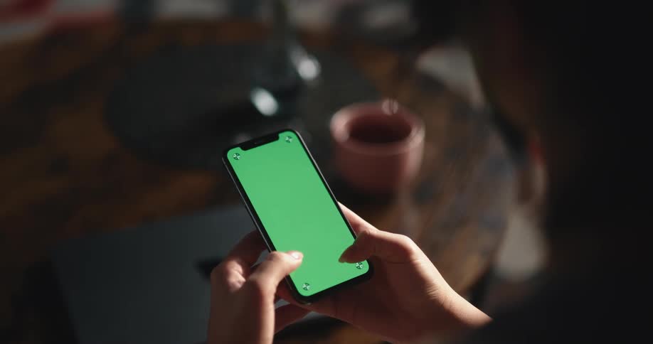 Woman with dark hair texts on smartphone next to brown coffee table