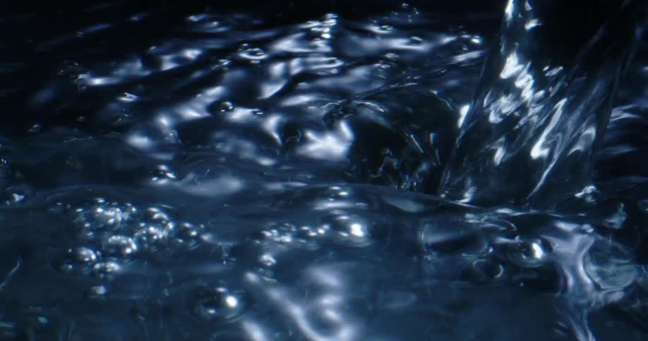 A thick stream of water is poured into a flowing tub of water