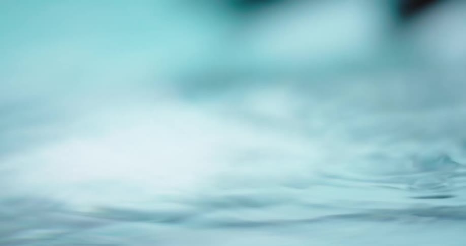 Close up of two hands creating small ripples and waves on the surface of a body of clear water