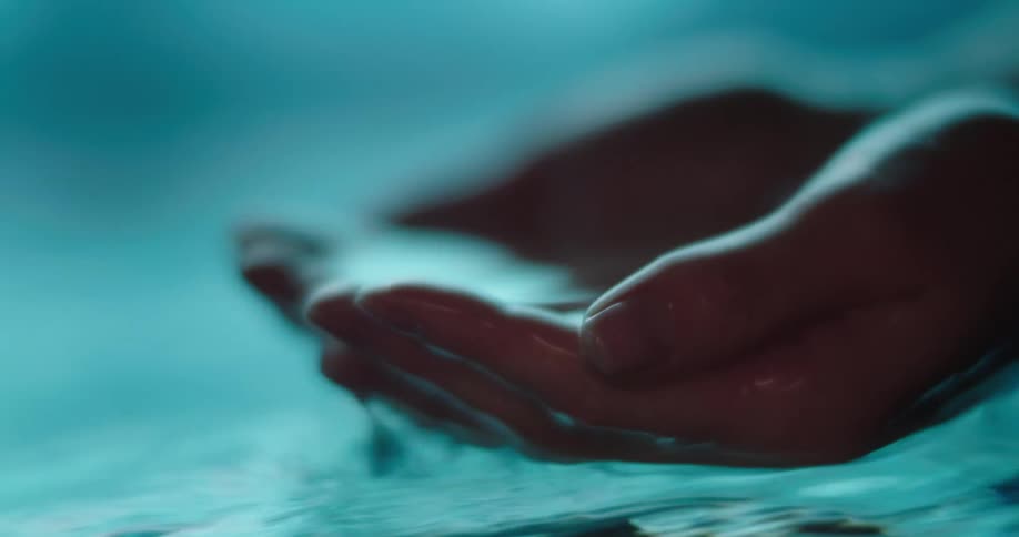 Submerging both hands cupped together in water and lifting out handful of water