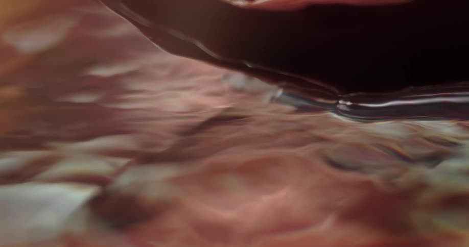 A persons hand emerging from water creating ripples and droplets