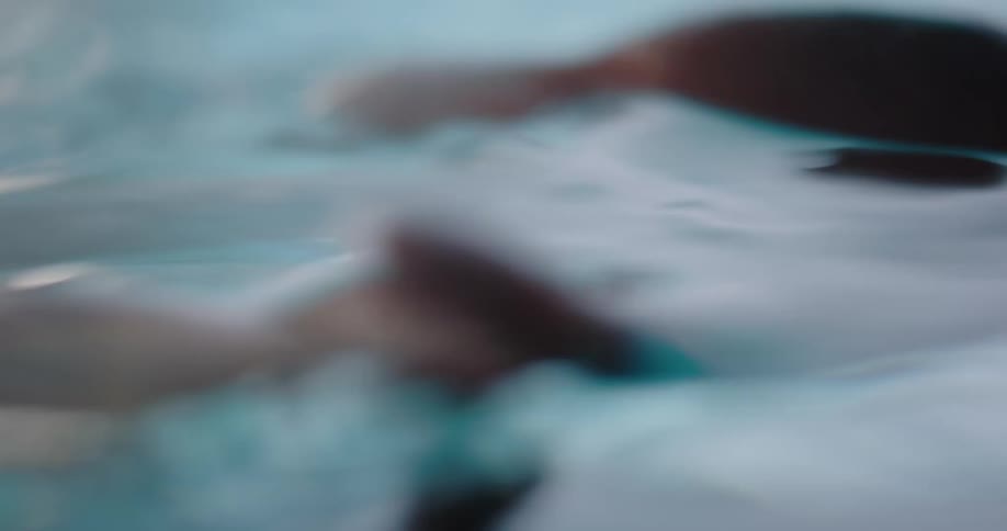 A woman runs her fingers through water while sitting in a pool